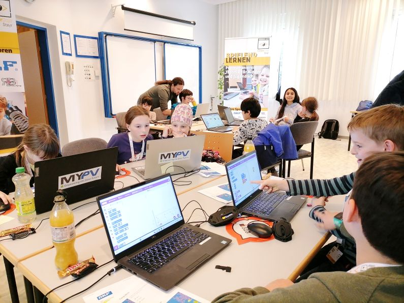 Kinder sitzen vor Laptops und Programmieren im Rahmen des CoderDojos Steyr in der SKF Österreich AG.