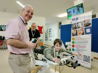 Ein Kind auf einem ICAROS Trainer und zwei Erwachsene daneben.